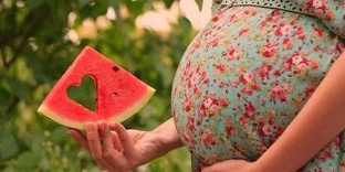 vattenmelonskiva i handen på en gravid kvinna